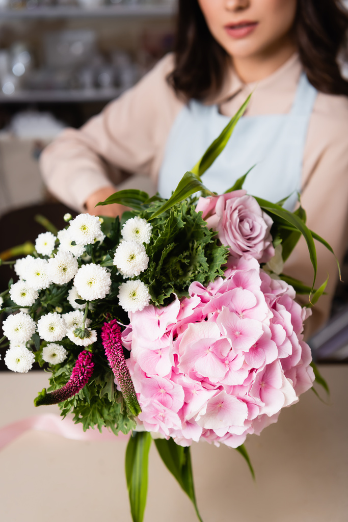 Close up view of fresh bouquet with blurred female florist on background - Photo, Image