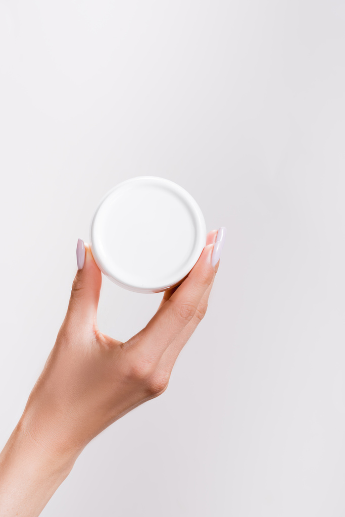 cropped view of woman holding container of hand cream isolated on grey - Photo, Image