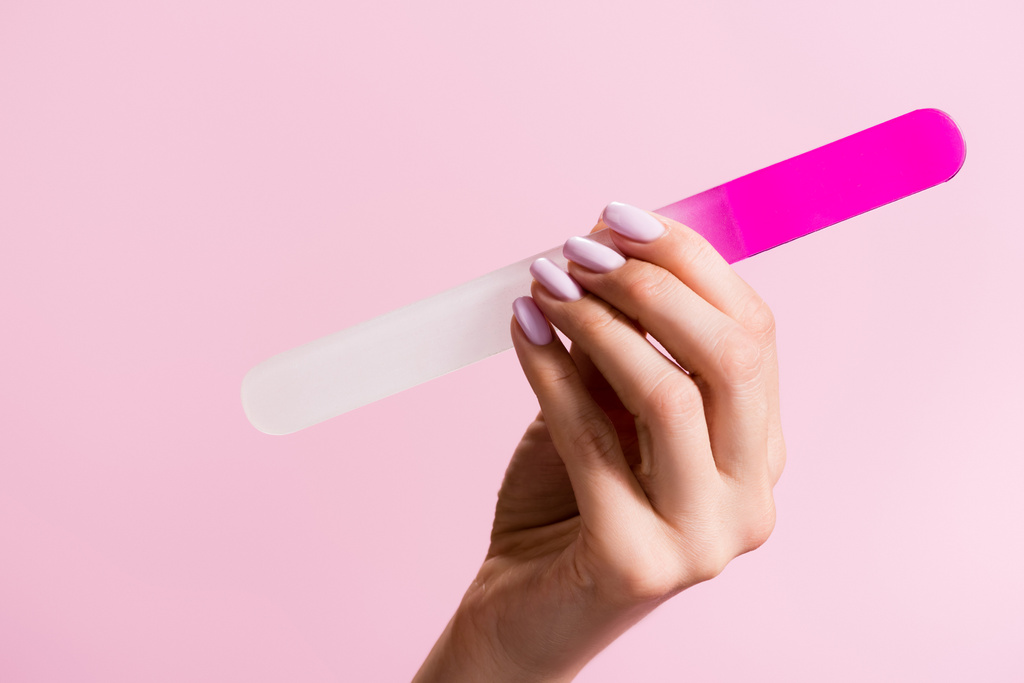 vista recortada de la mujer sosteniendo la lima de uñas aislado en rosa - Foto, imagen