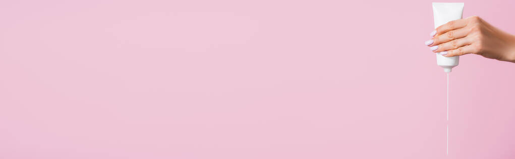 vista recortada de la mujer apretando crema de manos aislado en rosa, bandera - Foto, Imagen