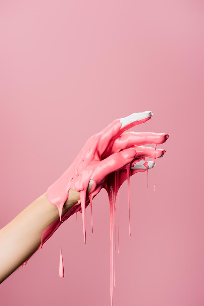 oříznutý pohled na ruku s kapající barvou izolovanou na růžové - Fotografie, Obrázek