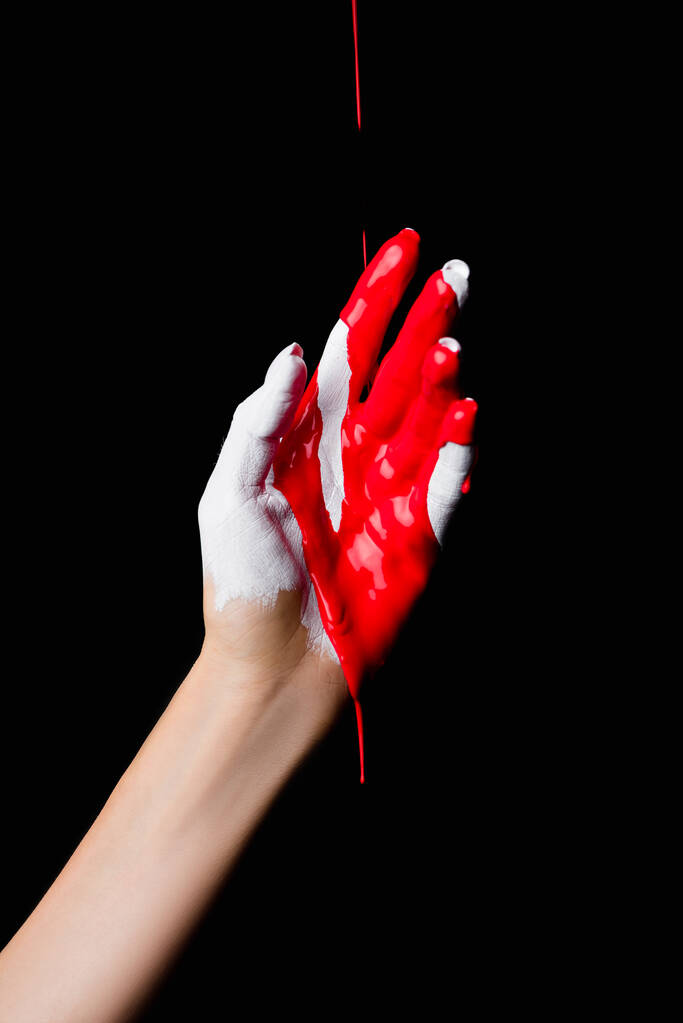 vue partielle de la main peinte en blanc avec peinture rouge goutte à goutte isolée sur noir - Photo, image