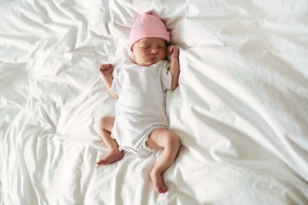 Una dulce niña recién nacida durmiendo en una cama blanca - Foto, imagen