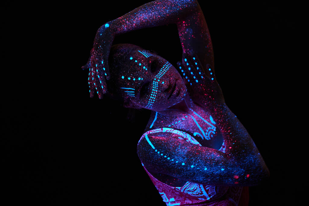 紫外光の中の芸術女性の宇宙。体全体が色液滴で覆われています。暗闇の中でポーズをとる少女。ノイズ、集中力を失い - 写真・画像