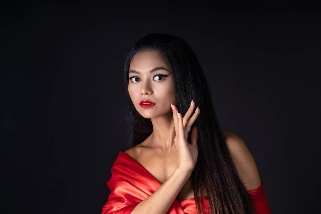 auf schwarzem Hintergrund chinesische Mädchen mit roten Lippen und in einem roten traditionellen chinesischen Kleid - Foto, Bild