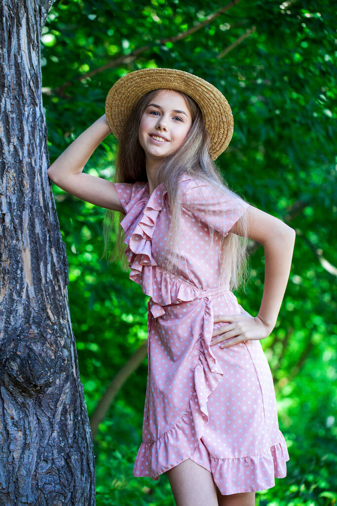 Retrato de una joven hermosa en un vestido de verano posando a la sombra de un roble - Foto, Imagen