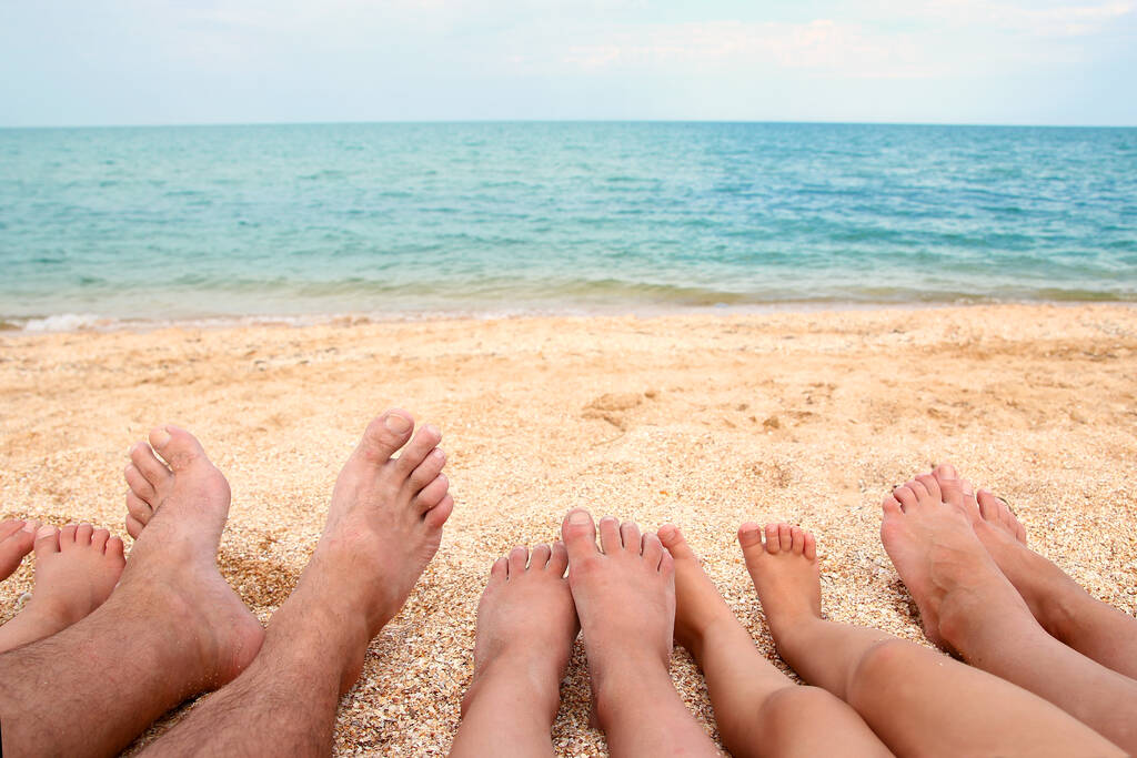 Kauniiden koko perheen jalat hiekalla lähellä merenpohjaa - Valokuva, kuva