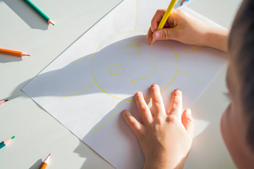 子供は鉛筆で太陽を描く。子供の創造性と芸術。就学前は幼稚園で絵を描くスキルを取得します。子供の保護の日 - 写真・画像