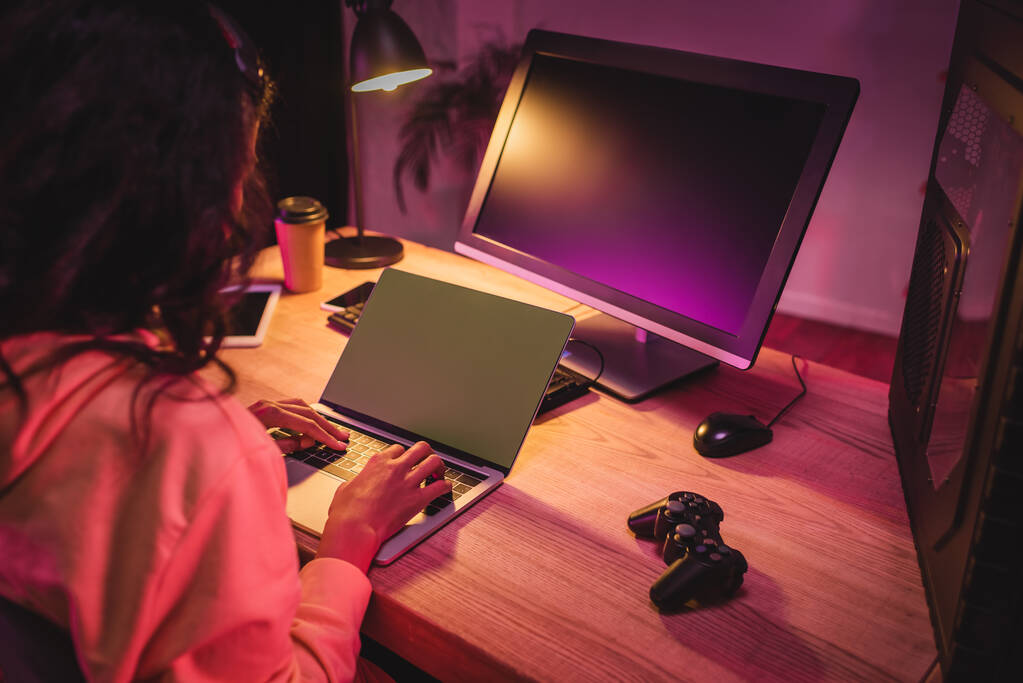KYIV, UCRANIA - 21 de agosto de 2020: Gamepad cerca de gamer afroamericano usando portátil en primer plano borroso  - Foto, imagen