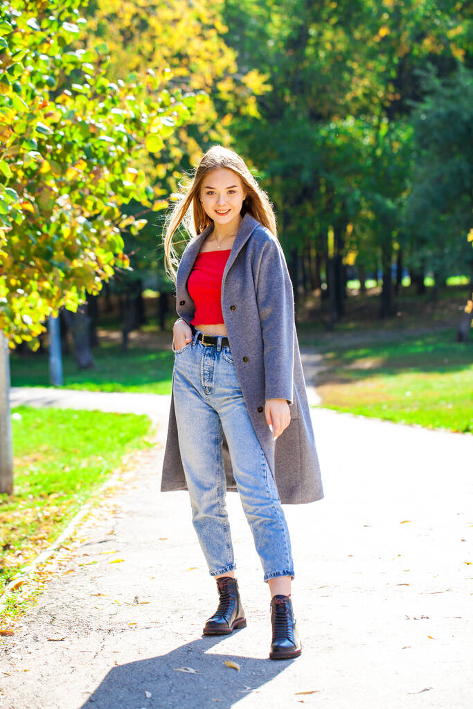 Retrato de corpo inteiro de uma jovem bela mulher loira de casaco cinza e jeans azul, parque de outono ao ar livre - Foto, Imagem