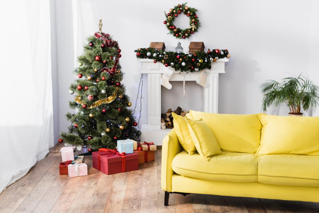 ingepakte cadeautjes onder kerstboom in gedecoreerde en moderne woonkamer - Foto, afbeelding