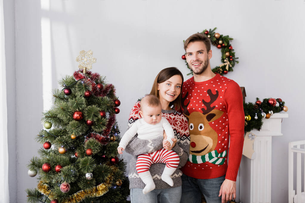 クリスマスツリーの近くに立っている男の子と幸せな家族 - 写真・画像