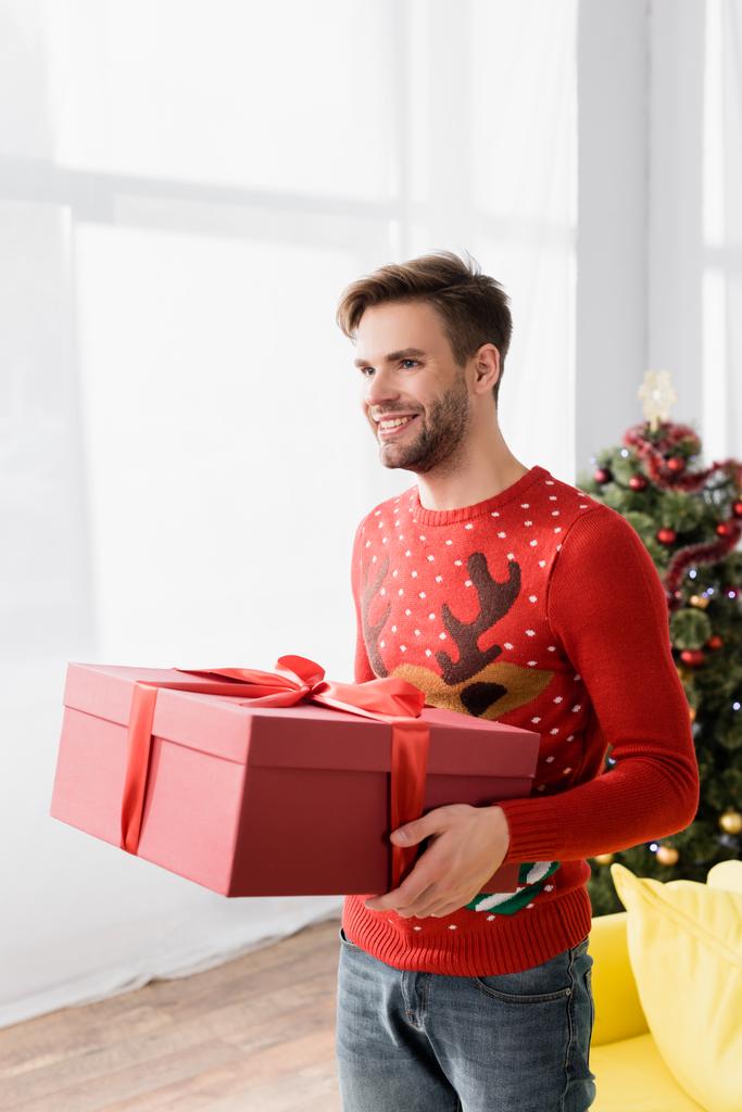 homem feliz em camisola vermelha segurando embrulhado presente de Natal  - Foto, Imagem