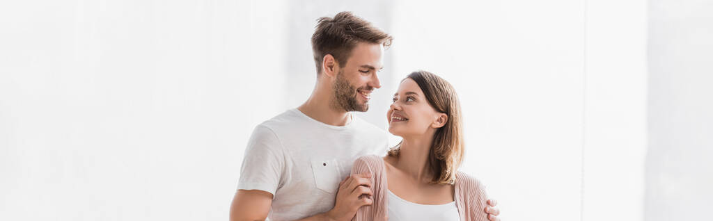 glücklicher Mann und Frau, die sich zu Hause umarmen, Banner - Foto, Bild