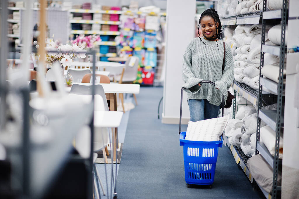 Африканская женщина с корзиной для покупок в современном магазине мебели для дома. - Фото, изображение