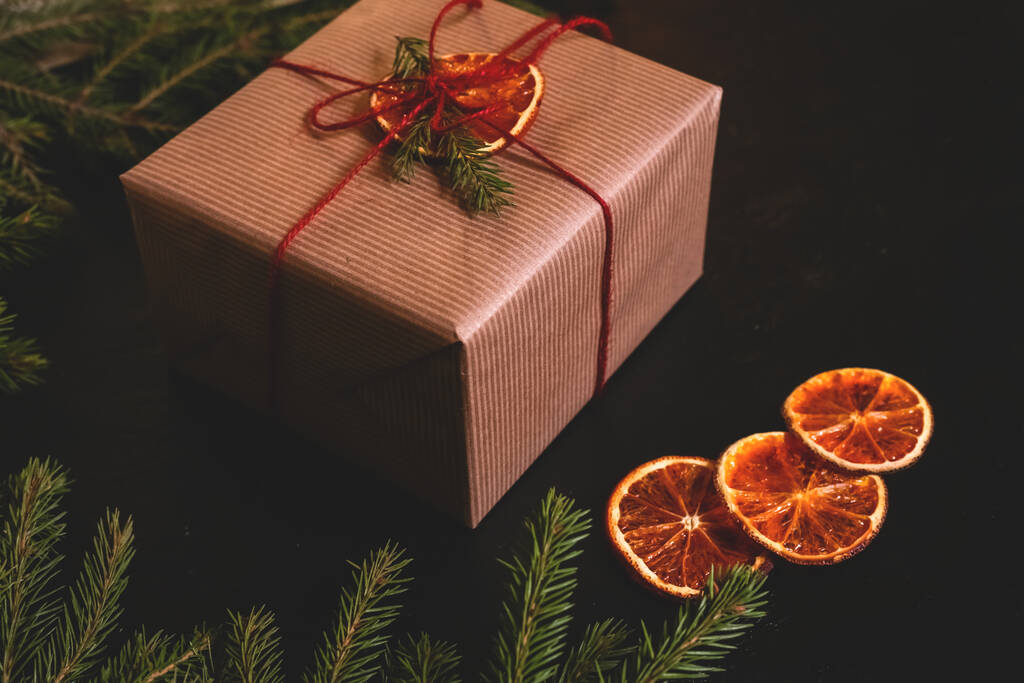 Weihnachtskomposition. Handgemachte Geschenkschachtel mit Bastelpapier mit Brunches auf dunklem Hintergrund. Kopierraum - Foto, Bild