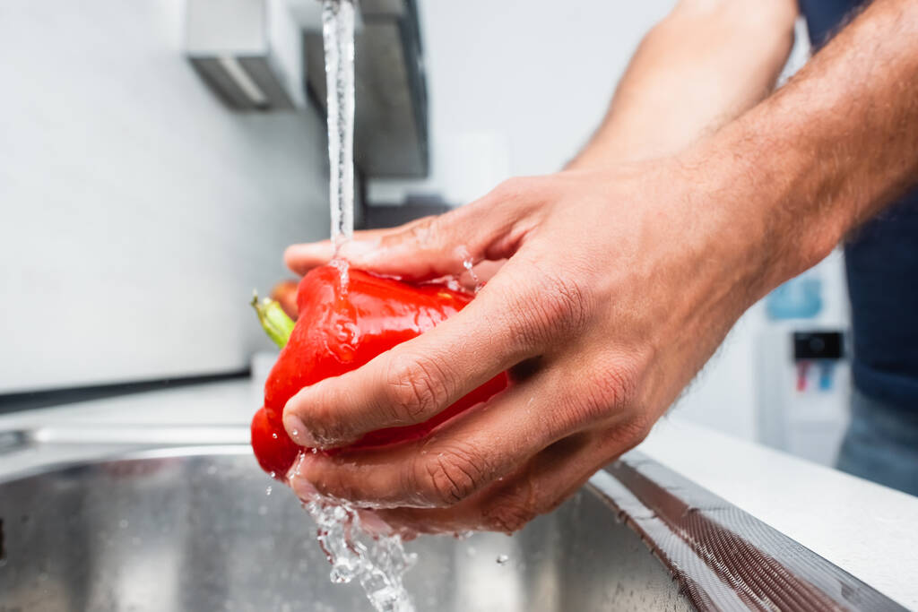 Close up view of man washing bell pepper in kitchen  - Fotografie, Obrázek