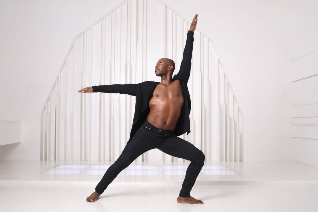 Elegant black man dancer in black clothes is dancing in a bright room. - Photo, Image