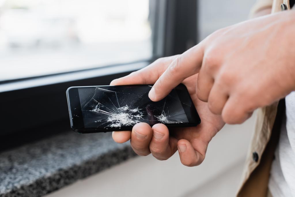 Обрізаний вид бізнесмена, який торкається розбитого сенсорного екрану смартфона на розмитому фоні
 - Фото, зображення