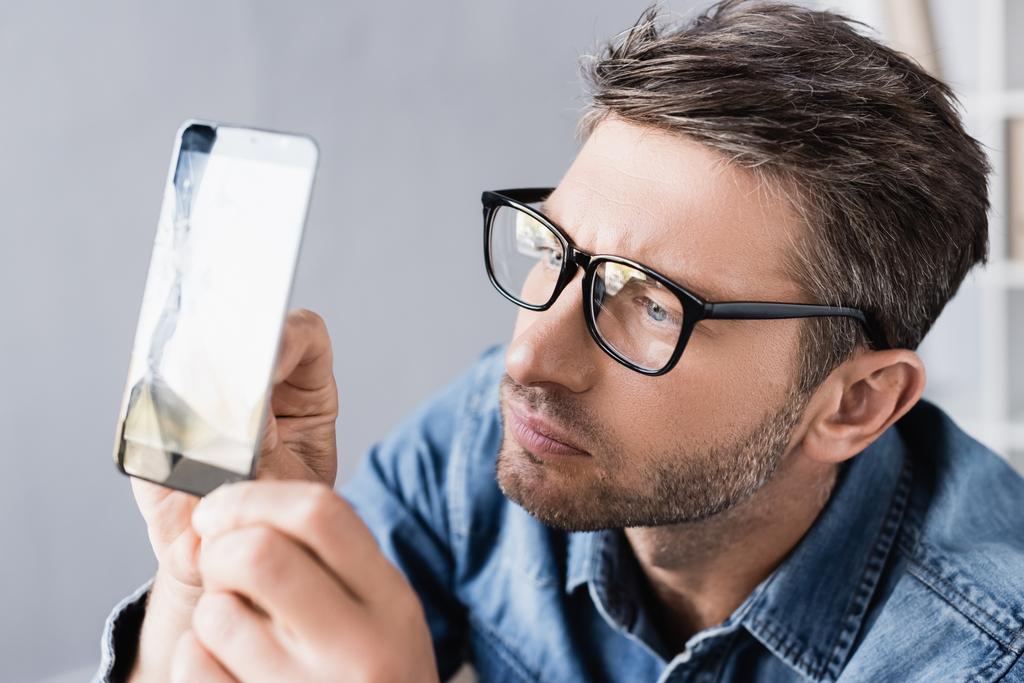 Орієнтований ремонтник в окулярах дивиться на зламаний сенсорний екран в офісі
 - Фото, зображення