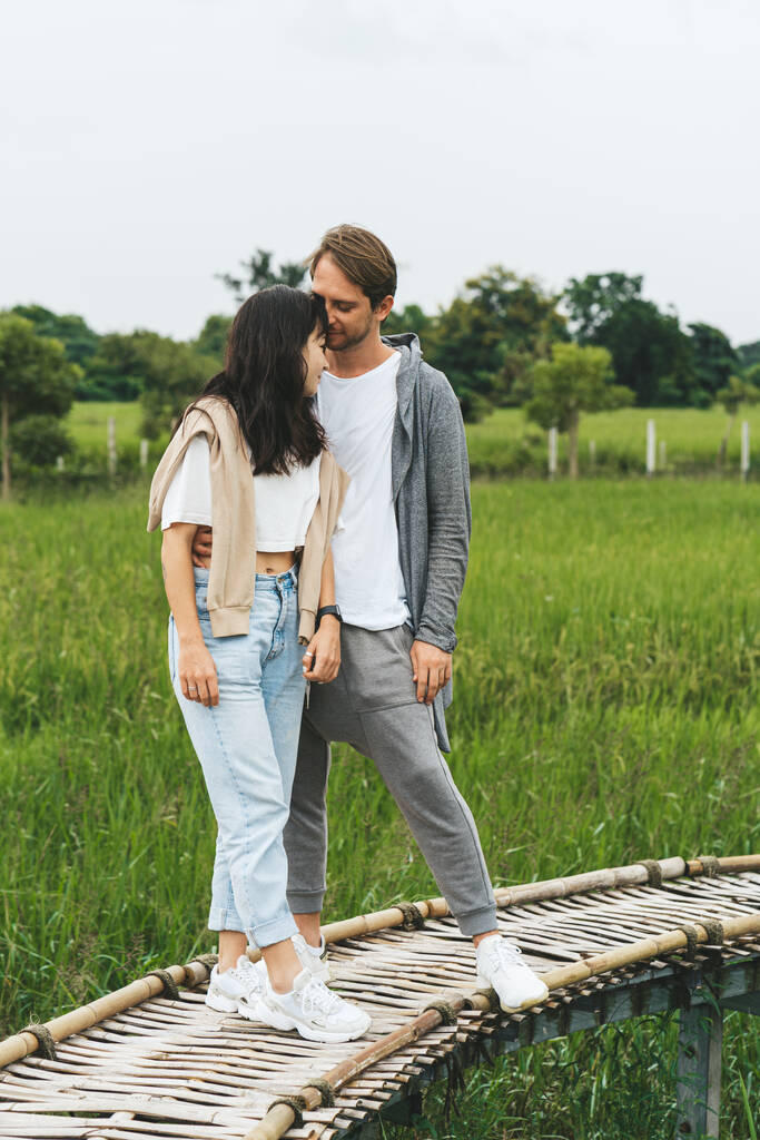 Para zakochanych stoi na bambusowym moście na polu ryżowym. - Zdjęcie, obraz