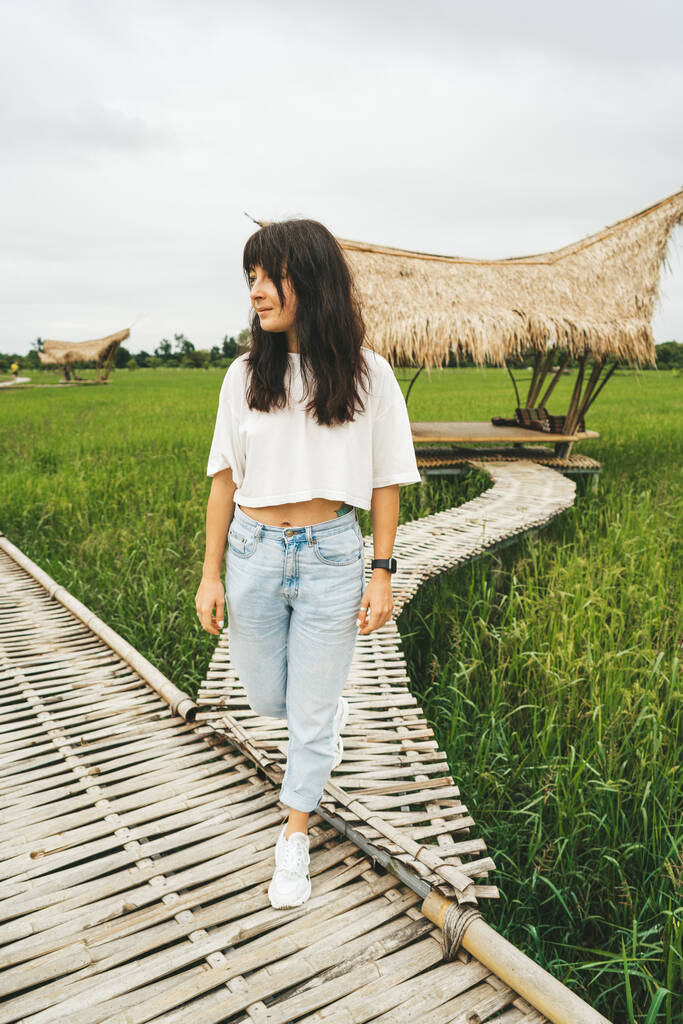 Kadın pirinç tarlasında bambu köprüsünde yürüyor. - Fotoğraf, Görsel