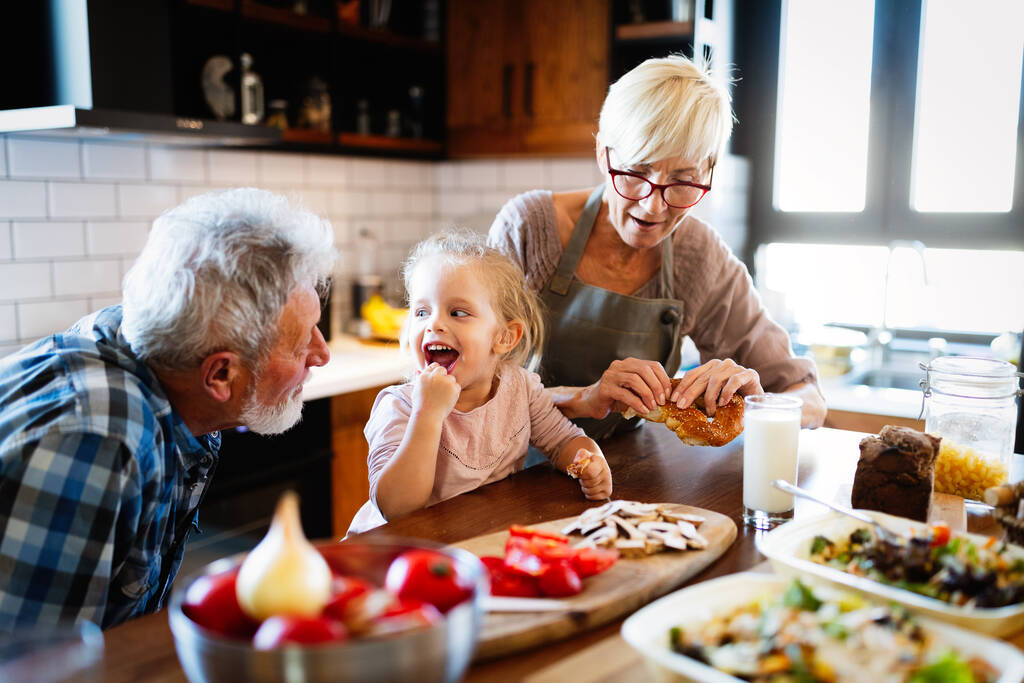 Glücklich lächelnde Großeltern spielen mit ihrer Enkelin - Foto, Bild