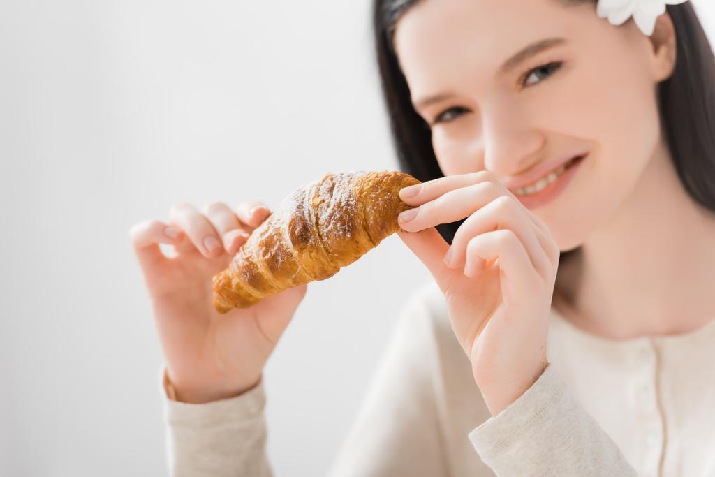 croissant in hands of happy woman with vitiligo on blurred background  - Photo, Image
