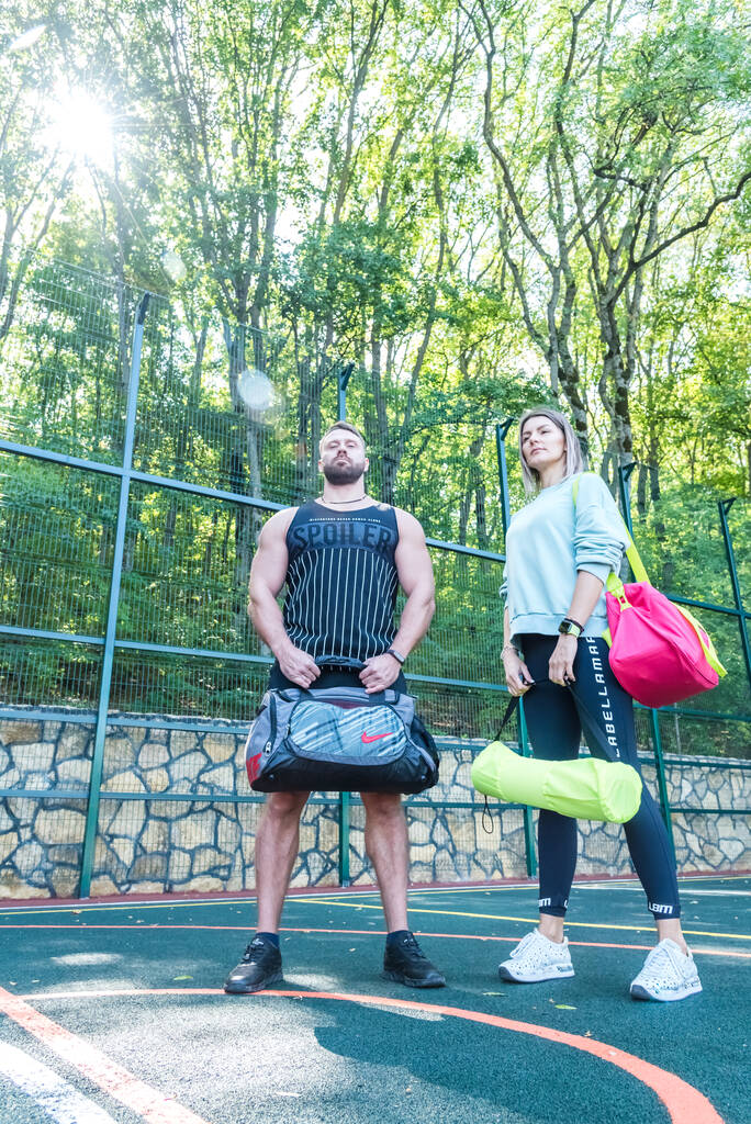 Muž a žena ve sportovním oblečení a se sportovním vybavením stojí venku na cvičišti. Zdravý životní styl koncept - Fotografie, Obrázek