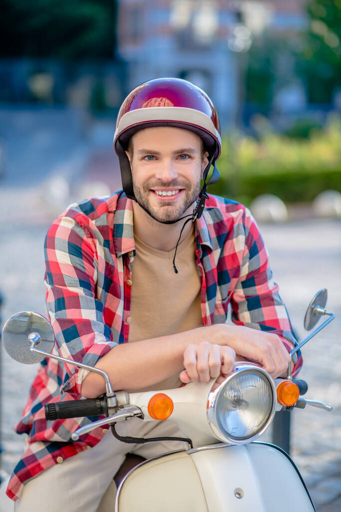 Joven hombre guapo en hemlet sentado en una scooter - Foto, Imagen