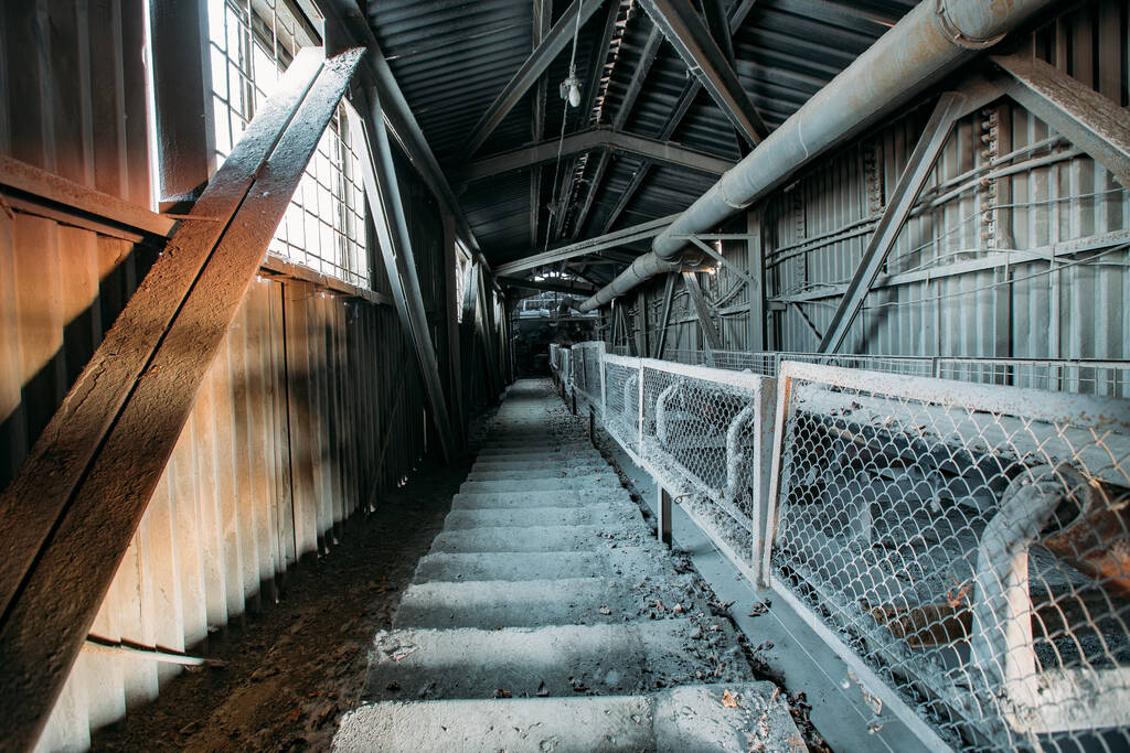 Abandoned cement and concrete factory. Old rusty conveyor in corridor - Photo, Image