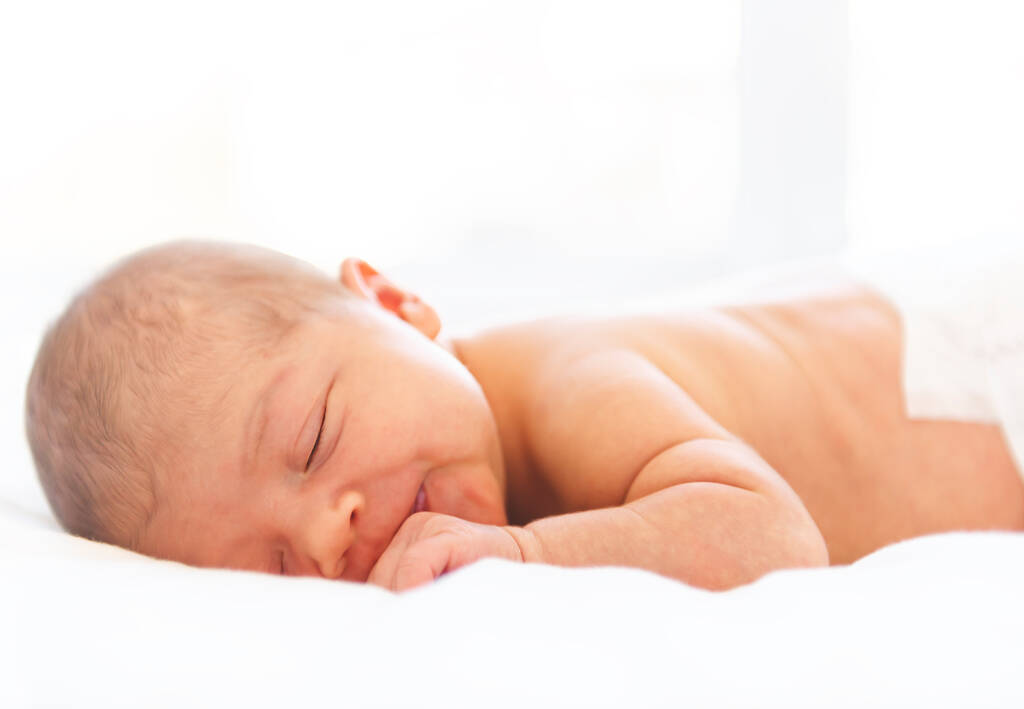 Um bebê recém-nascido deitado dormindo em um fundo branco suave. Use a foto para representar a vida, a paternidade ou a infância. - Foto, Imagem
