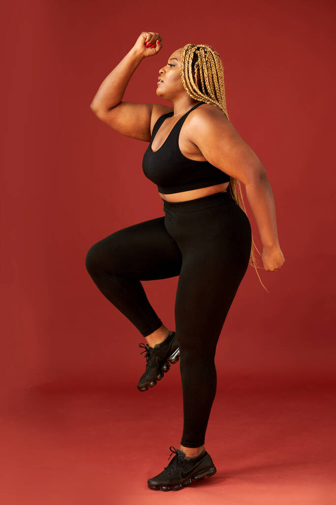 πορτρέτο της παχουλής Αφρικανή γυναίκα σε μαύρο αθλητικό ένδυμα κάνει ασκήσεις - Φωτογραφία, εικόνα