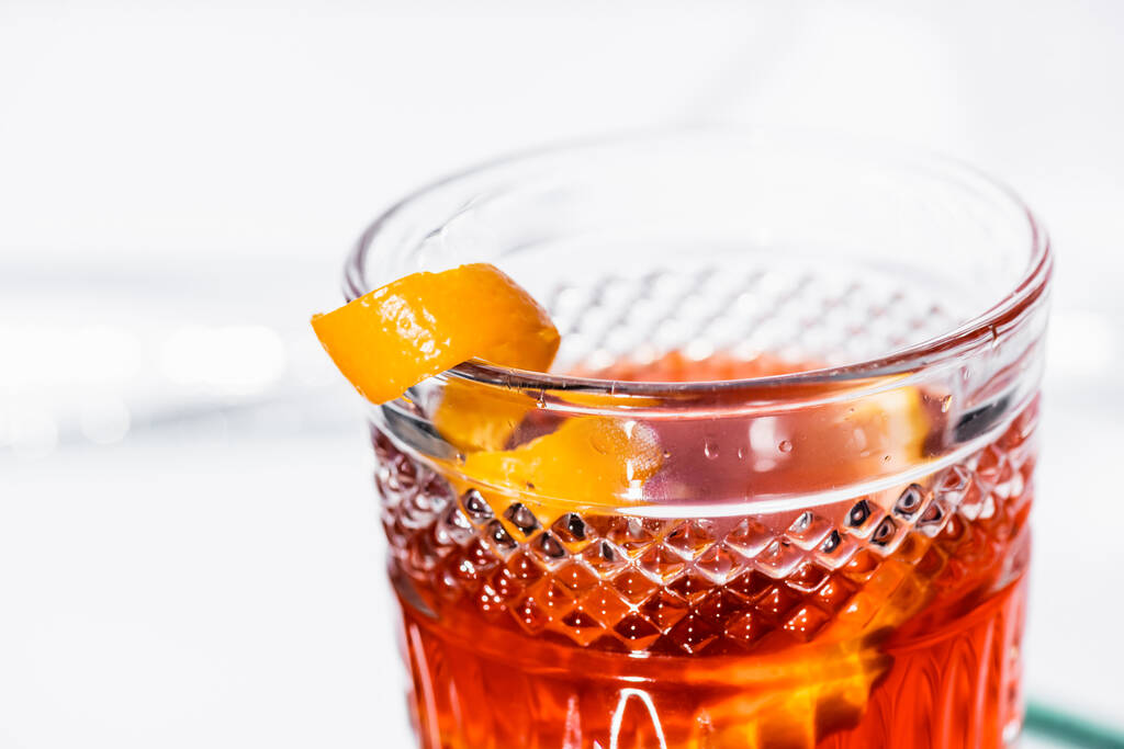 primo piano di buccia d'arancia in vetro con cocktail di alcool su bianco - Foto, immagini