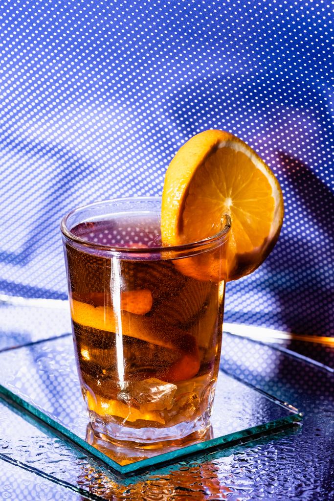 glas met gemengde cocktail en gesneden sinaasappel van blauw - Foto, afbeelding