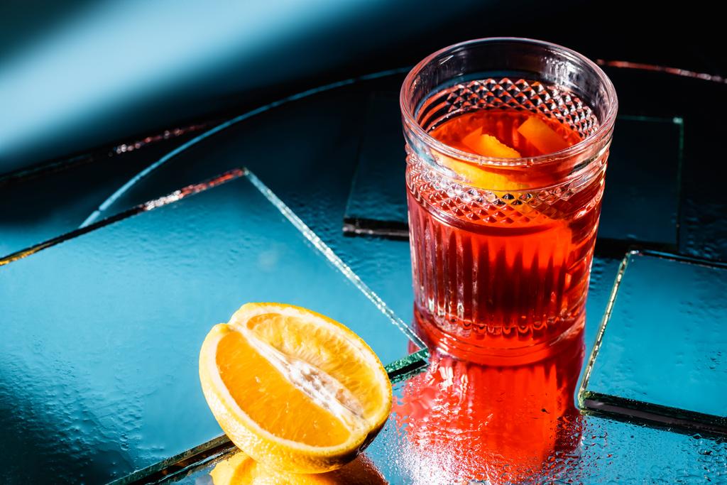 cóctel de alcohol mezclado cerca de la mitad de naranja en azul - Foto, imagen