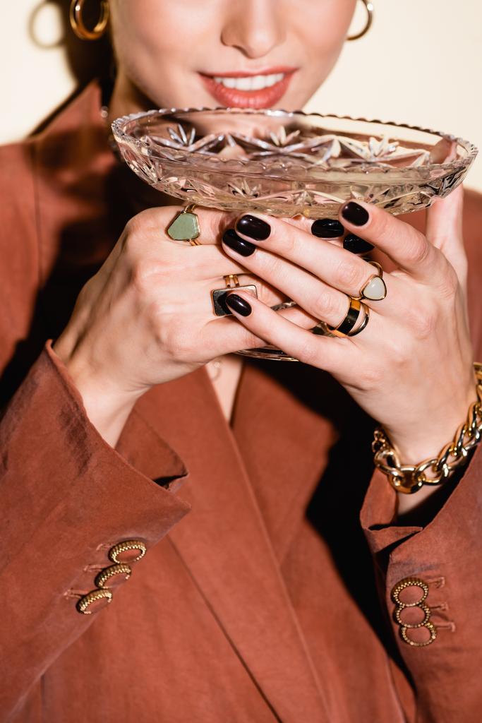 vista cortada de mulher feliz em blazer marrom bebendo champanhe de vidro em branco - Foto, Imagem
