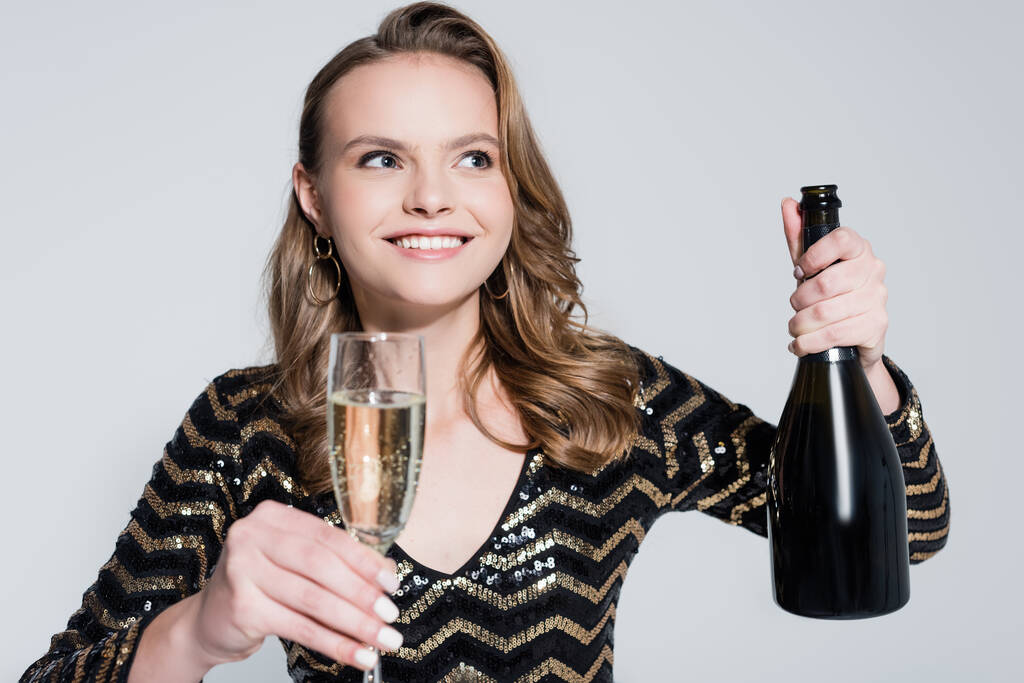 happy woman holding glass of champagne and bottle isolated on grey - Photo, Image