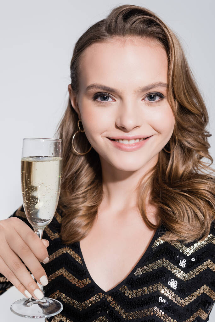 グレーで隔絶されたシャンパンのグラスを持つ笑顔の若い女性  - 写真・画像