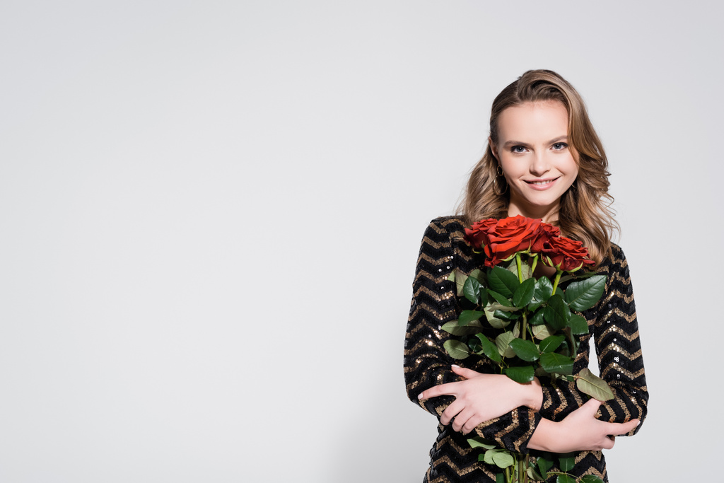 šťastná mladá žena drží kytice z rudých růží na šedé - Fotografie, Obrázek