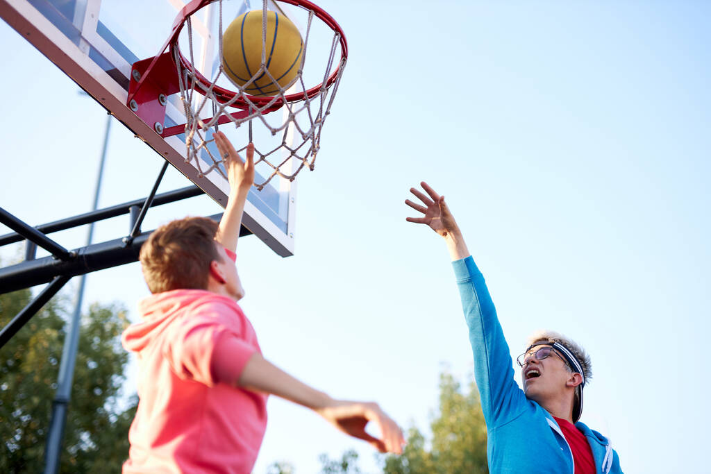 tizenévesek lövés kosár és kosárlabda, alsó nézet széles látószög - Fotó, kép