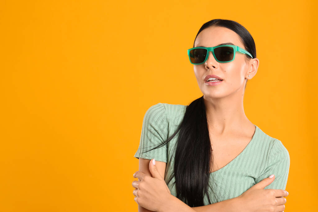 Schöne Frau mit Sonnenbrille auf gelbem Hintergrund. Raum für Text - Foto, Bild