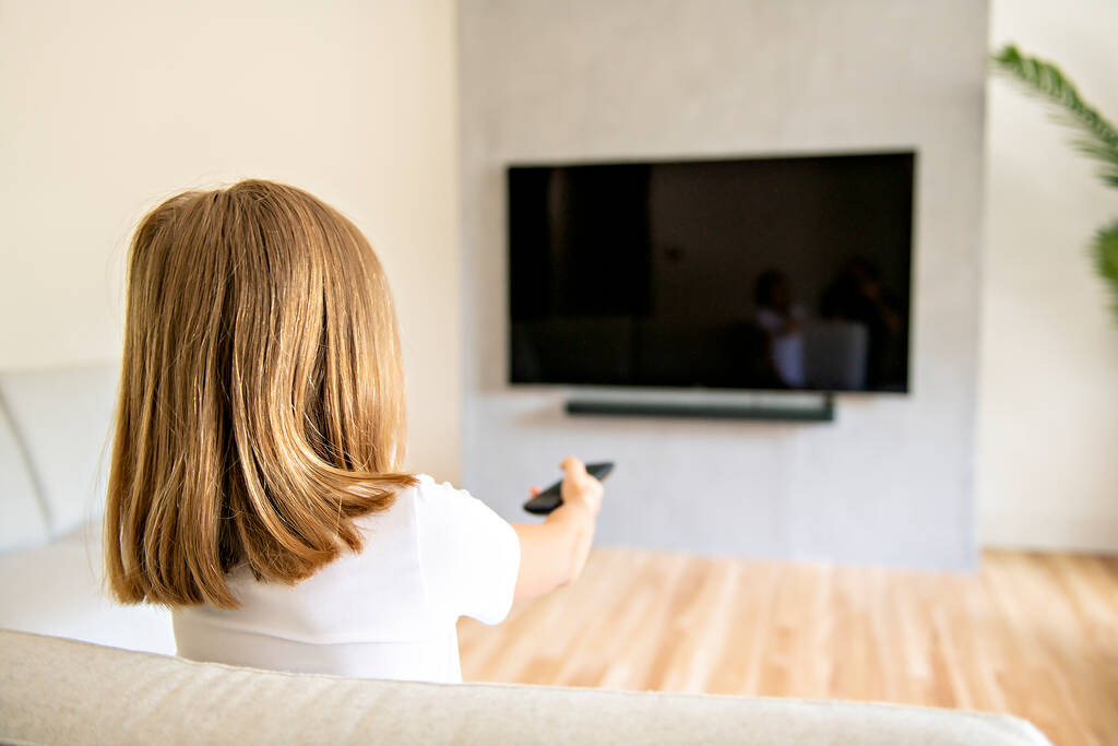 Takaisin Katso kuva söpö pieni vaaleat hiukset tyttö istuu sohvalla ja katsella televisiota. - Valokuva, kuva
