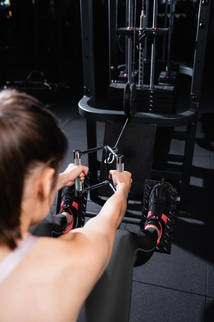 zpět pohled sportovkyně cvičit na veslování stroj na rozmazané popředí - Fotografie, Obrázek