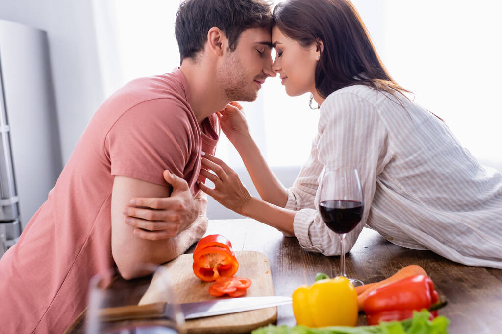 Giovane donna toccare fidanzato vicino al vino e verdure fresche in primo piano sfocato  - Foto, immagini