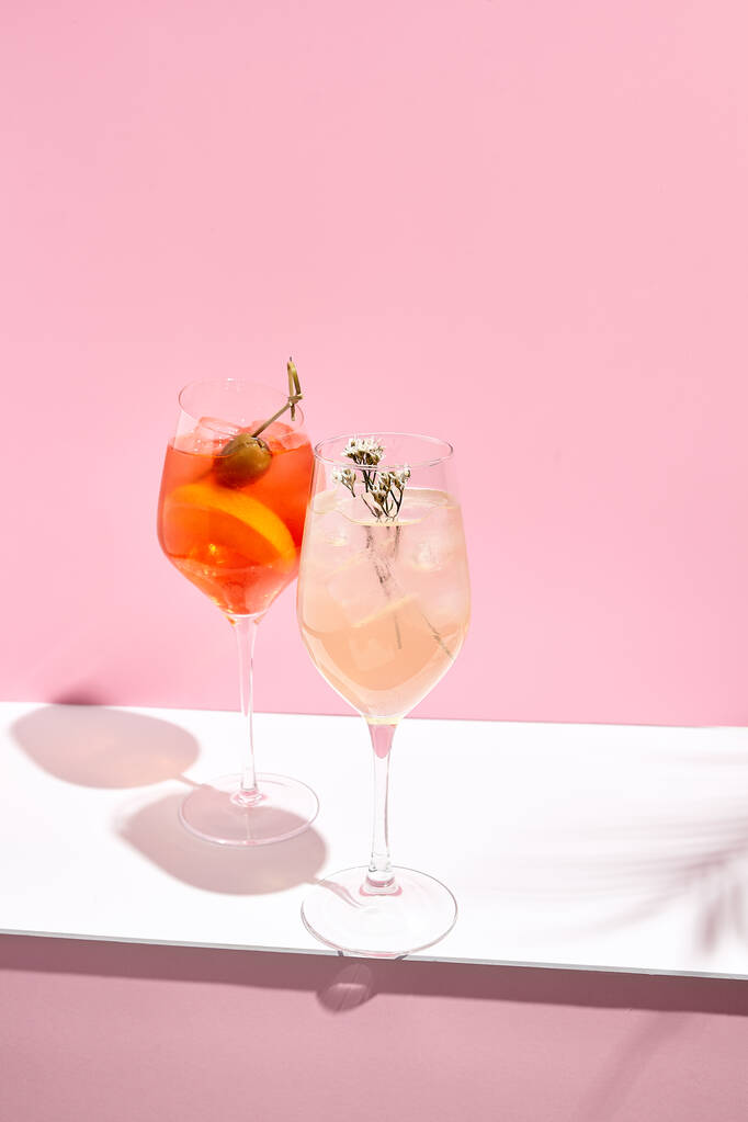 Aperol Spritz Cocktail sur fond rose. Lumière du soleil et fond d'ombre. Rose et blanc minimal - Photo, image