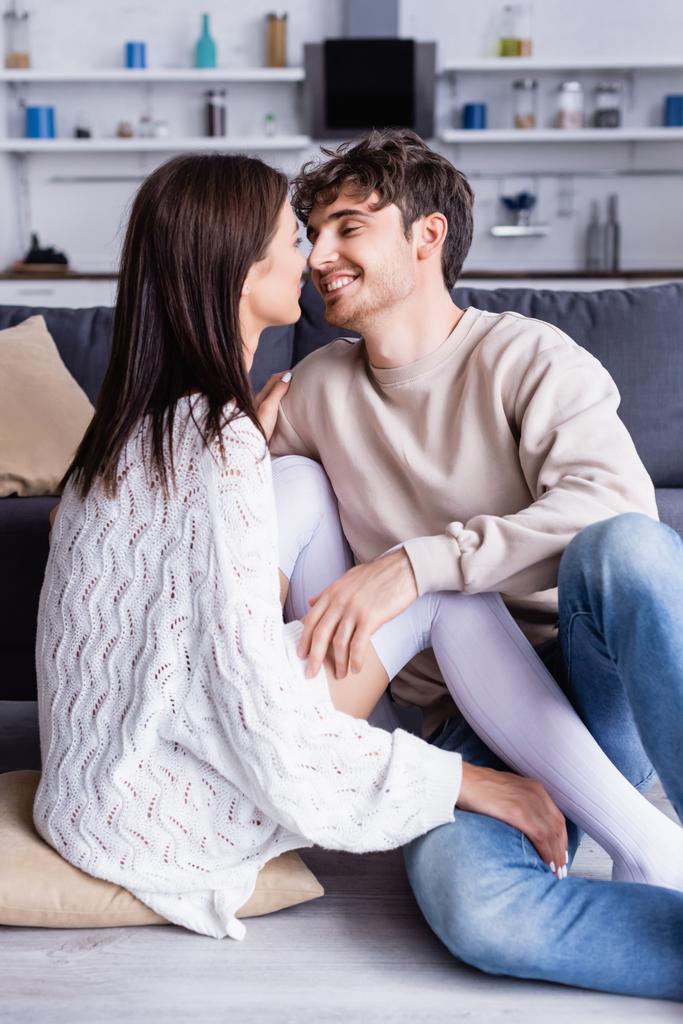 glimlachende man aanraken vriendin in knie sokken op vloer  - Foto, afbeelding