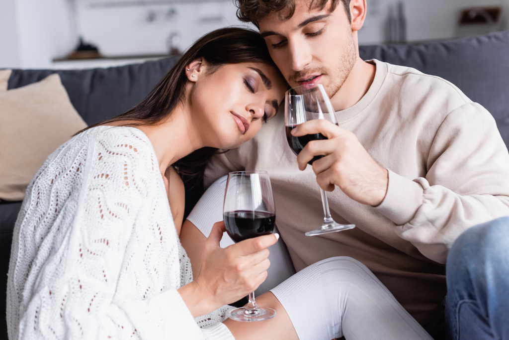 Brunette nainen tilalla lasi viiniä lähellä poikaystävä kotona  - Valokuva, kuva