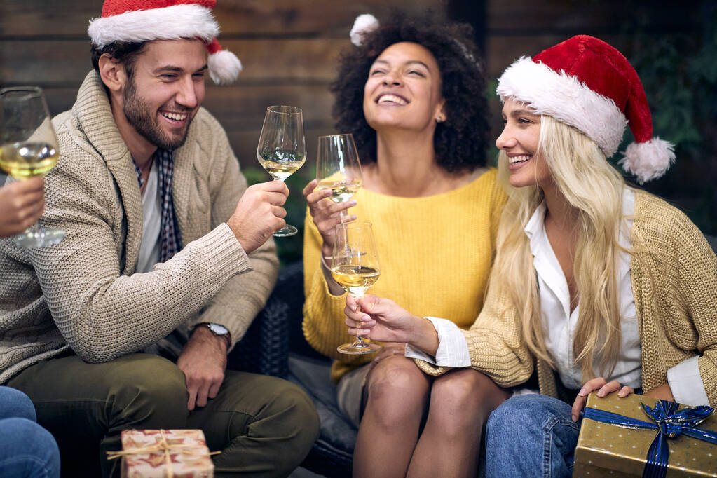 Gruppo di giovani allegri che si godono lo champagne in un'atmosfera festosa a Natale o a Capodanno insieme. Natale, amici, brindisi, divertimento, concetto di festa - Foto, immagini
