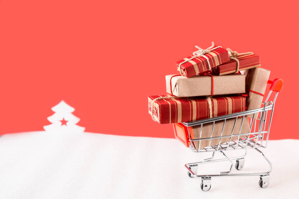 Carrito de compras con regalos sobre fondo rojo navidad - Foto, imagen